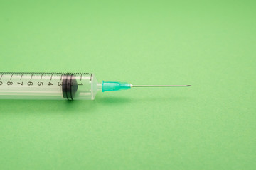 Medical syringe on green background, health and vaccination concept.