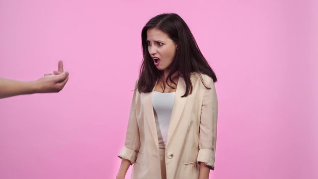 dissatisfied girl refusing gift box, man showing middle finger to shocked girl looking at camera Isolated On pink