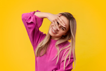 Cheerful young woman looking at camera through fingers