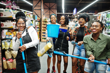 Obraz na płótnie Canvas Group of five african womans with dust mop, toilet brush and bucket having fun in household cleaning items department in supermarket.
