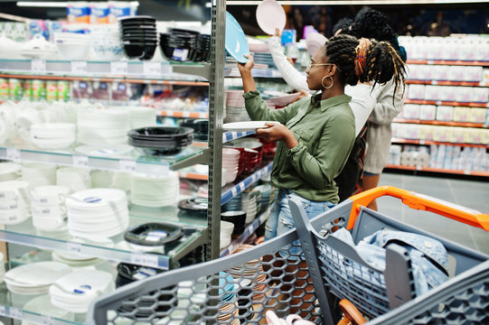 Group of african womans look color plates on supermarket shelves.