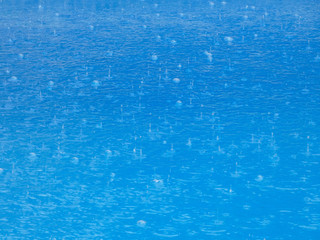 Lluvia cayendo sobre el agua de una piscina; tormenta descargando el agua sobre el agua de una piscina