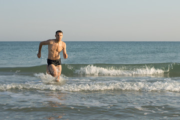 A man runs through the waves at sea