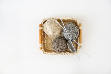 balls of yarn of natural shades of wool in a basket on a white background, a set for knitting