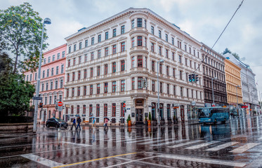 Obraz premium Rainy day in Vienna, Austria. Wet streets, puddles, pedestrians with umbrellas and public transport