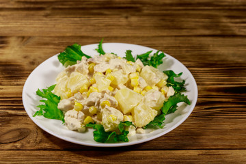 Festive salad with chicken breast, sweet corn, canned pineapple and mayonnaise on wooden table
