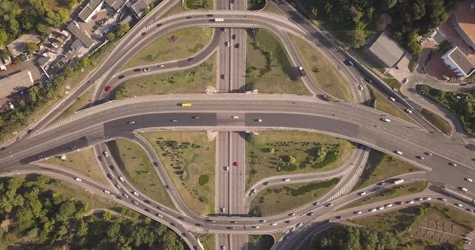Aerial high drone in 4K flight over evening road traffic in Kiev, Ukraine. Highway and overpass with cars and trucks, interchange, two-level road junction in the big city. Top view. 