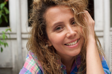 Close up happy woman smiling with hand in curly hair