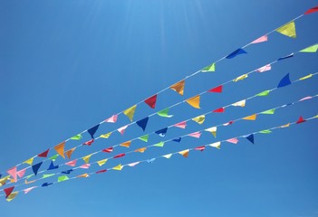 Colorful triangular flag buntings against clear blue sky