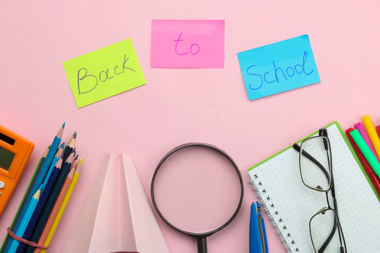Text back to school and various school supplies on a bright pink background. Office tools. education. top view.