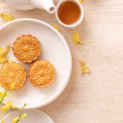 Delicious moon cake for Mid-Autumn festival with beautiful pattern, decorated with yellow flowers and tea. Concept of festive afternoon pastry design