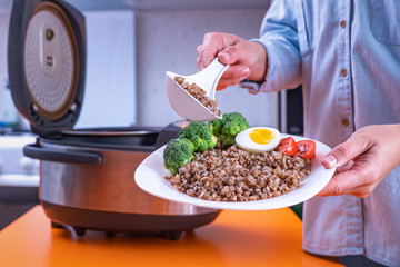 Woman cooking meals using multi cooker at home