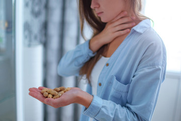 Young sick woman suffers from choking and cough from allergic reaction to peanut. Danger of nuts...