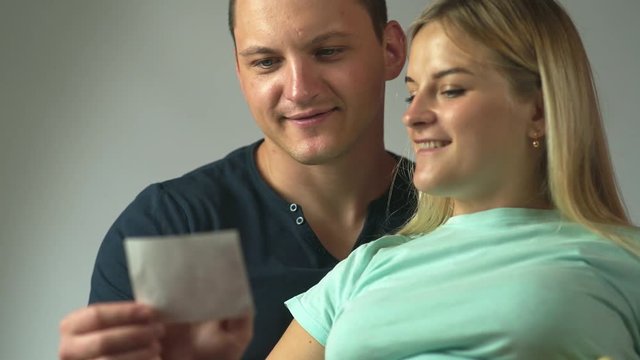 Happy family. Lovely pregnant couple holding ultrasound image of their baby. Mom and Dad feeling happy 