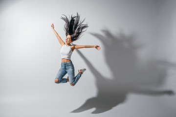 full length view of excited girl jumping with hands in air