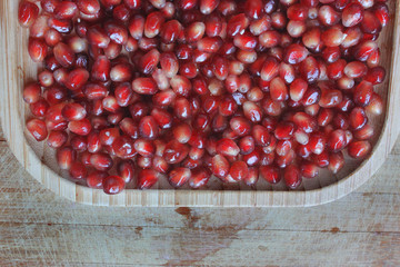 Garnet seeds in a wooden plate on a wooden table