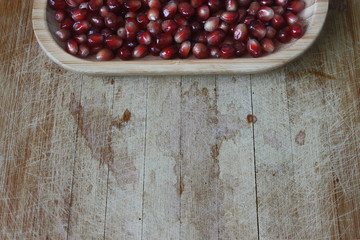 Garnet seeds in a wooden plate on a wooden table