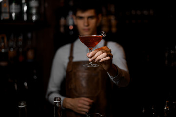 Close shot of bartender holding drink with olive