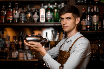 Portrait of young bartender in apron with shaker
