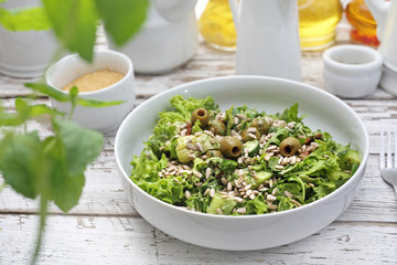 Green salad with olives, sun-dried tomatoes, sunflower seeds served with a sauce based on oil and herbs.