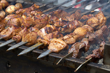 pieces of meat are friend on fire on skewers on grill. close up