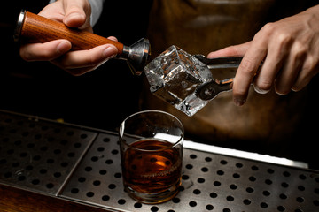 Bartender takes ice cube off ice picker