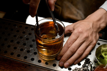 Bartender adding an ice cube in whiskey