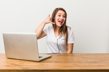 Young telemarketer woman showing a mobile phone call gesture with fingers.