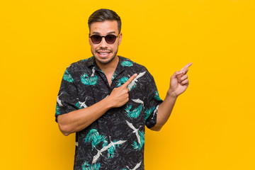 Young filipino man wearing summer clothes shocked pointing with index fingers to a copy space.