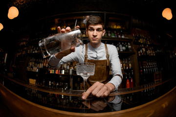 Fototapeta na wymiar Young bartender pours cocktail from a jar