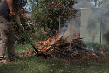 Man tending to fire controlled burn off of garden waste