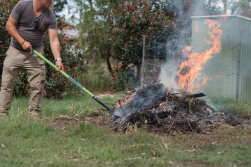 Man tending to fire controlled burn off of garden waste