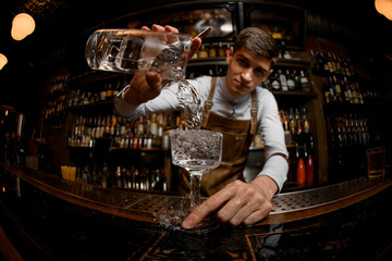 Young bartender pours drink from a jar