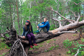 Naklejka na ściany i meble two young people are sitting on a fallen tree
