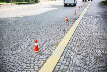 Traffic cones on the stone road. No parking signs.
