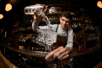 Young bartender pours drink from the jar