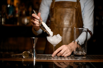 Bartender puts crushed ice in glass with scoop