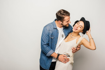 beautiful couple in stylish clothes dancing and laughing on white