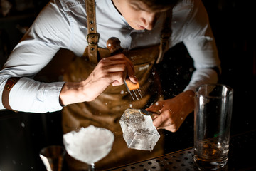 Bartender crushing piece of ice with crusher
