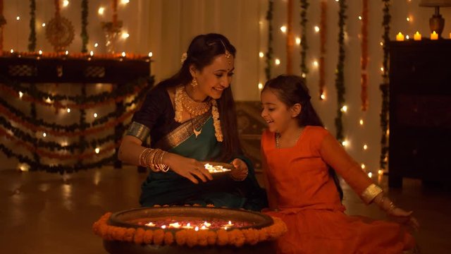 Beautiful Indian mother and daughter celebrating the Indian festival - Diwali Concept. Mother and daughter decorating their house together. Beautifully decorated house with candles  lights  and flo...