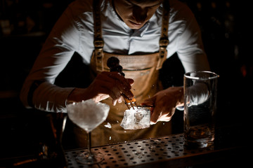 Bartender crushing an ice cube with crusher