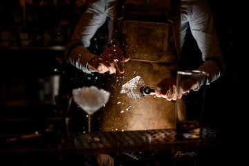 Bartender crushing an ice cube with picker