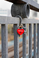 Red padlock in the form of heart and with the words "Me&you" hanging on fence