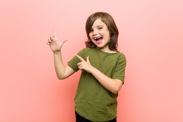 Little boy pointing with forefingers to a copy space, expressing excitement and desire.