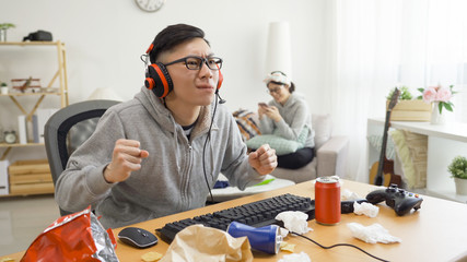 Angry young male gamer in glasses playing game on computer using headphones lose on internet...