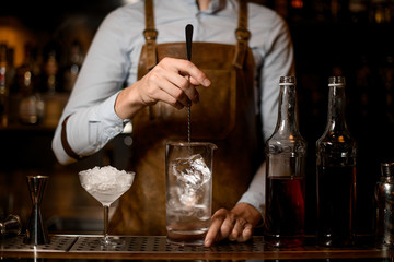 Bartender stirs alcohol cocktail with special spoon