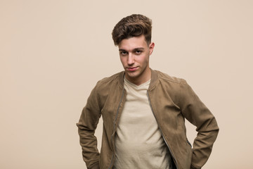 Young caucasian man wearing a brown jacket confident keeping hands on him hips.