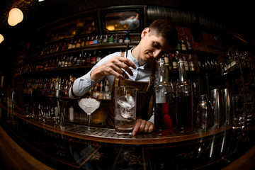 Bartender stirs alcohol drink with special spoon