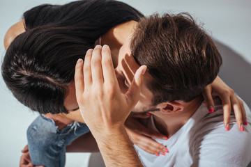 Fototapeta premium top view of young couple kissing while man hiding faces with hand