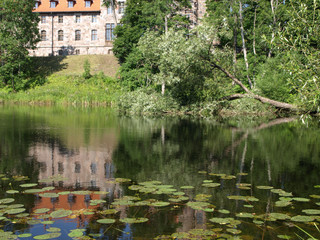 Obraz premium Cesvaine stone castle, beautiful summer day, pond, reflections, Latvia